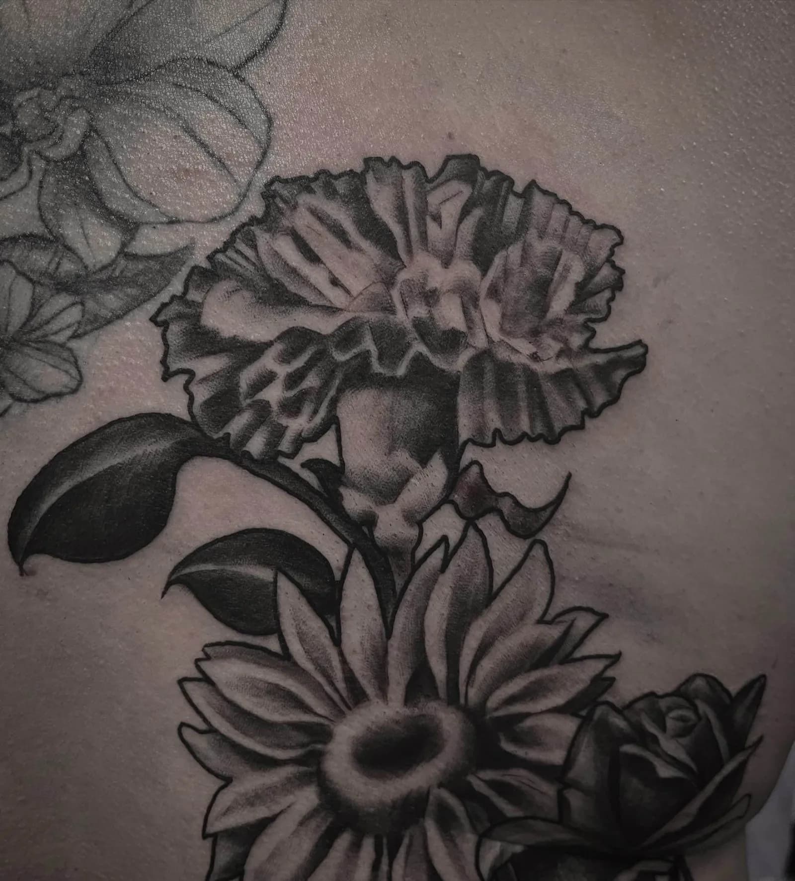 Black and grey floral chest piece with carnation, sunflower, and rose by Creative Tat at Shadow Studio Charlotte
