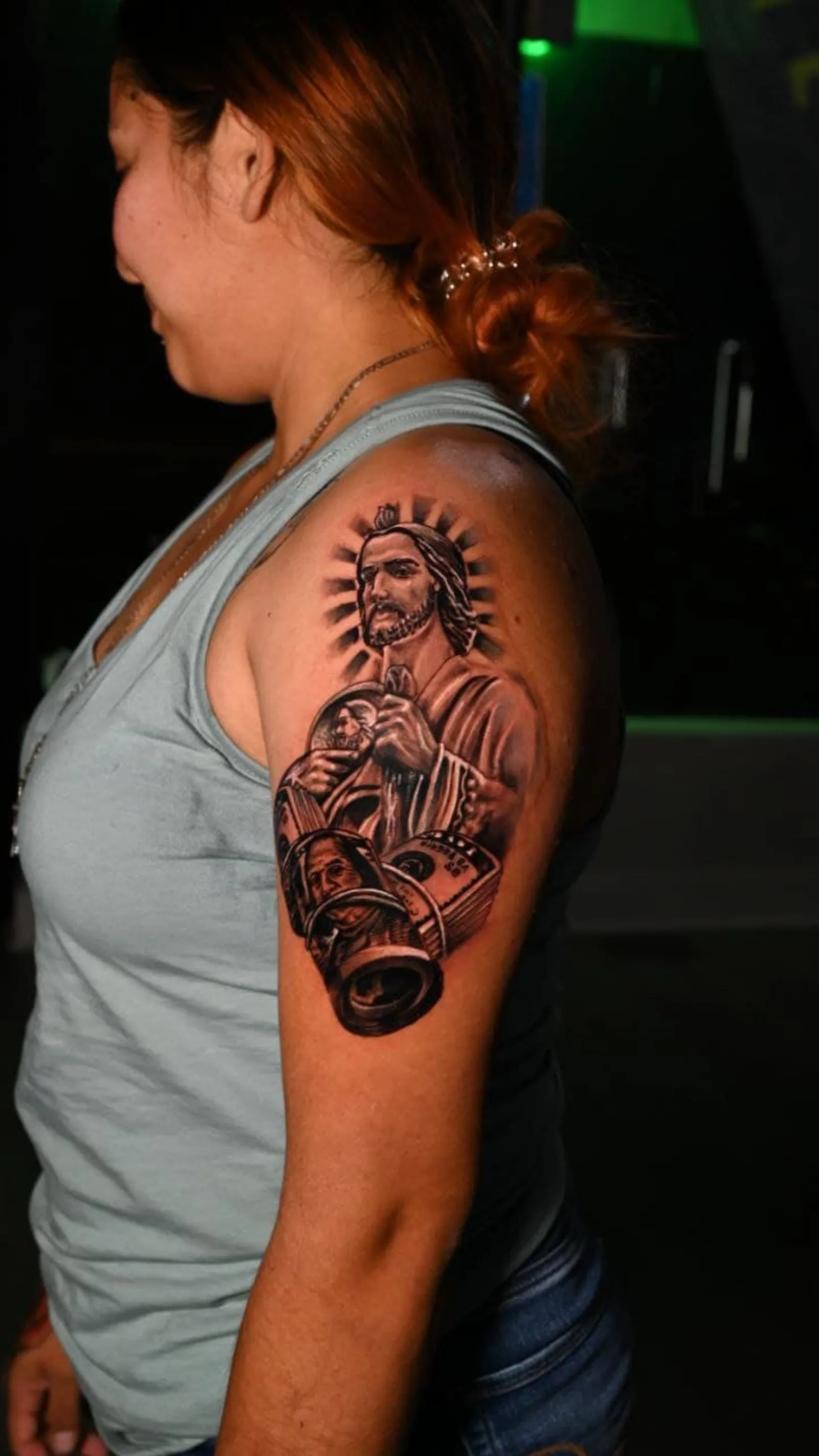 Black and grey upper-arm tattoo of the Virgin of Guadalupe holding a camera by Fresiato at Shadow Studio Charlotte