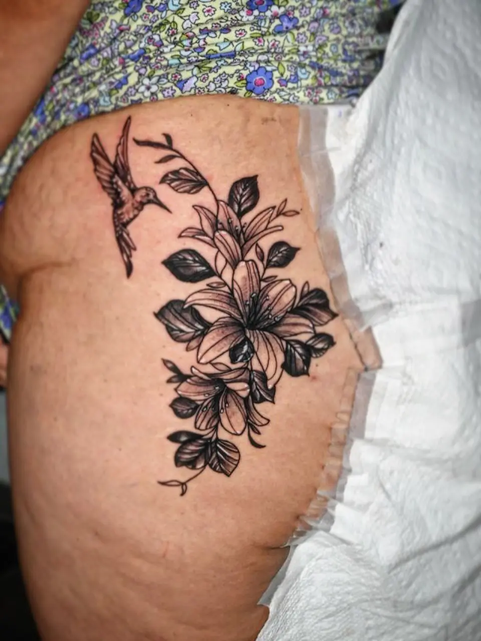 Black and grey hummingbird and lily floral hip tattoo by Fresiato at Shadow Studio Charlotte