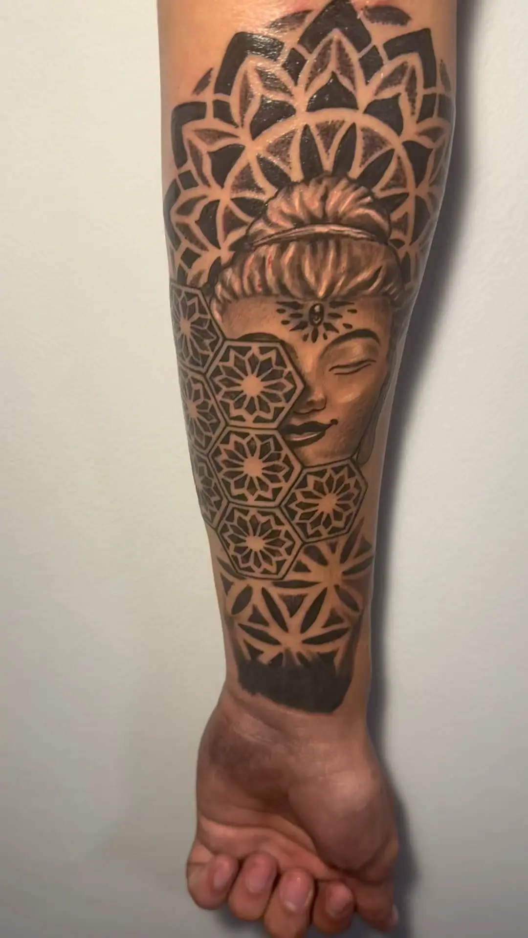 Black and grey geometric dotwork forearm sleeve with a serene face inside a mandala and sacred geometry by Fresiato at Shadow Studio Charlotte