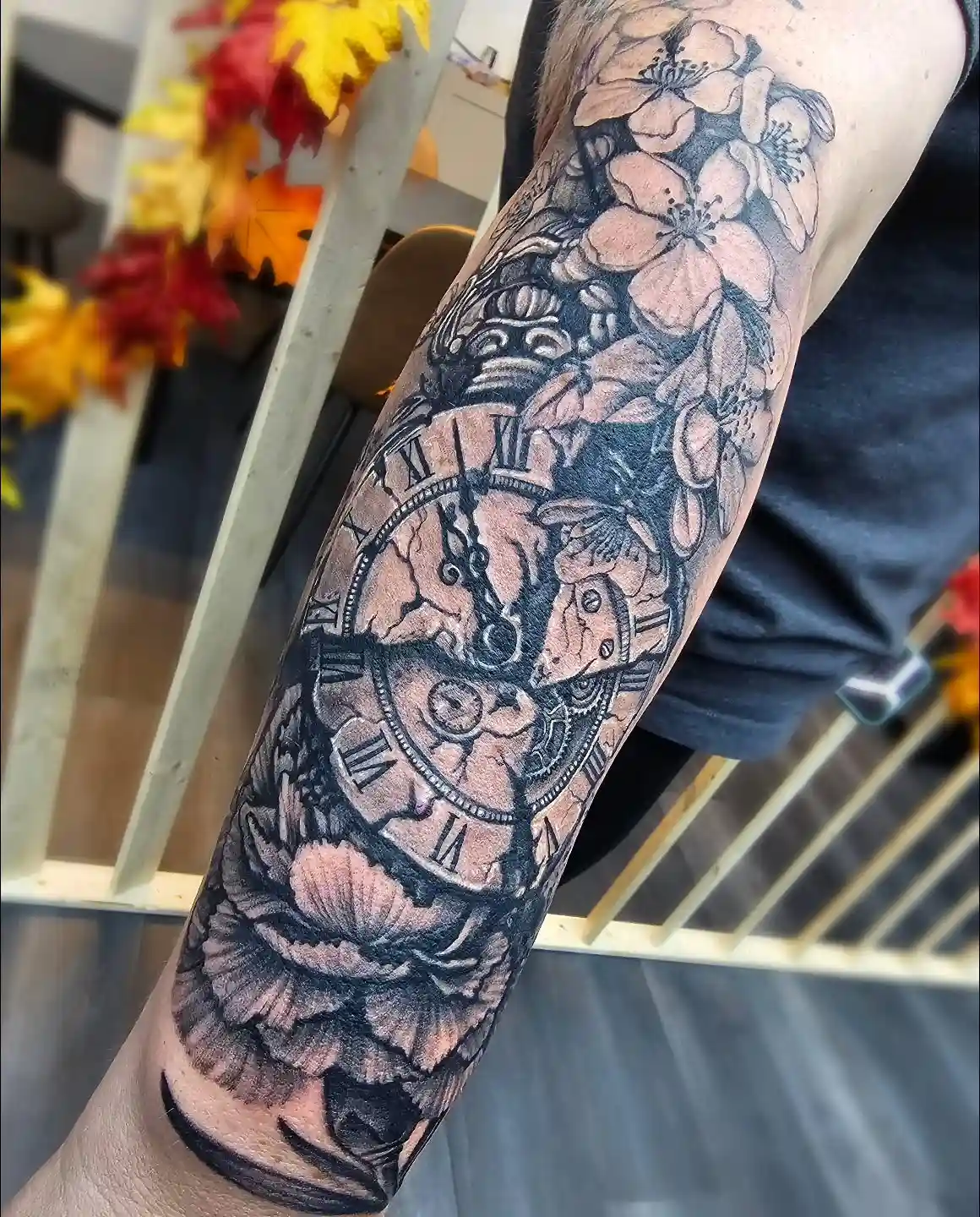 Black and grey neo-traditional forearm sleeve with Roman-numeral pocket watch, blossoms, and peony by Joel at Shadow Studio Charlotte